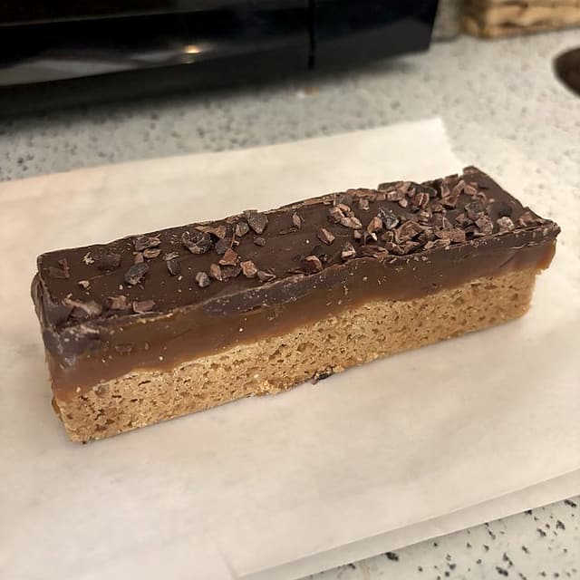 A Truckee bar: a layered bar with a caramel middle and a chocolate top sprinkled with cacao nibs