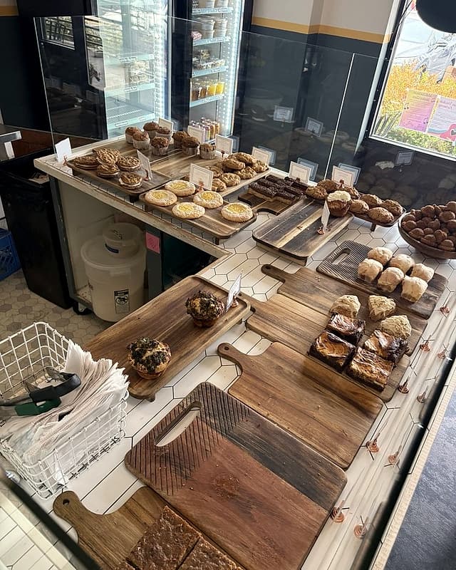 The bakery counter: wooden boards of bars, muffins and scones on white hex tile