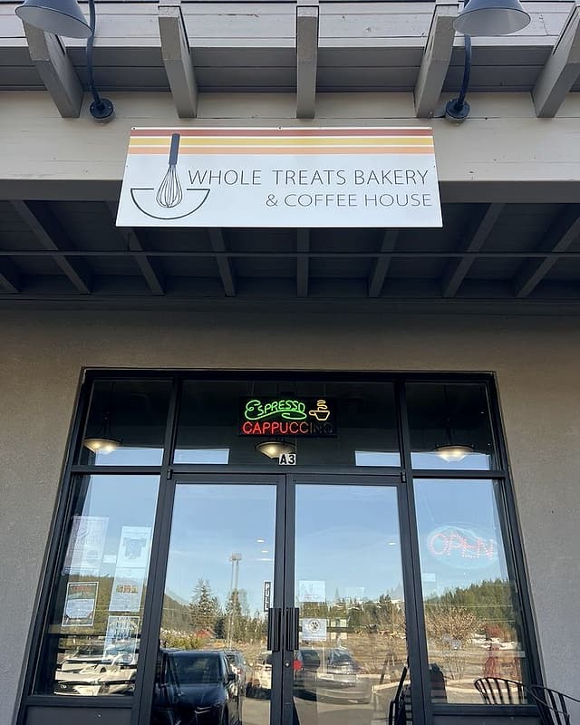 The storefront: a white Whole Treats Bakery & Coffee House sign with stripes over glass doors and a neon espresso sign